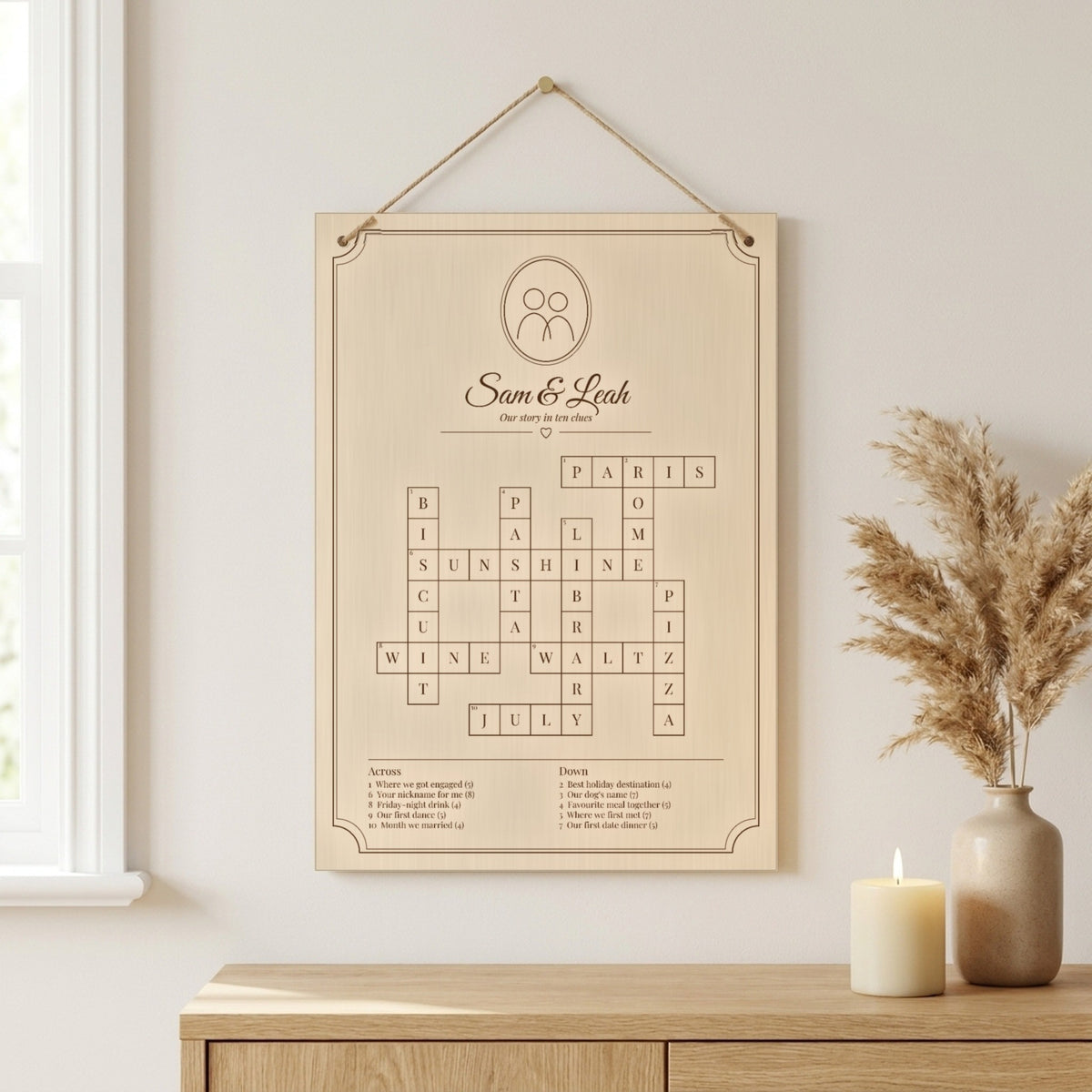 Personalised wooden crossword board engraved with a couple's names, hanging on jute twine
