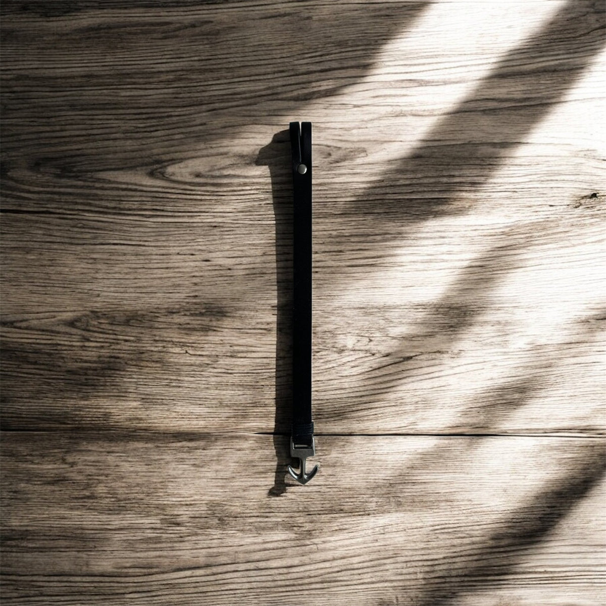 Black anchor bracelet for men on a wooden table