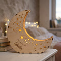 Personalised wooden moon lantern engraved Amelia glowing on a bedside table (illustration)