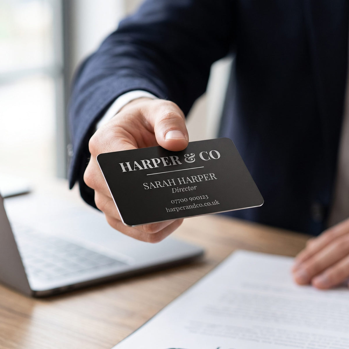 Professional handing over an engraved metal business card