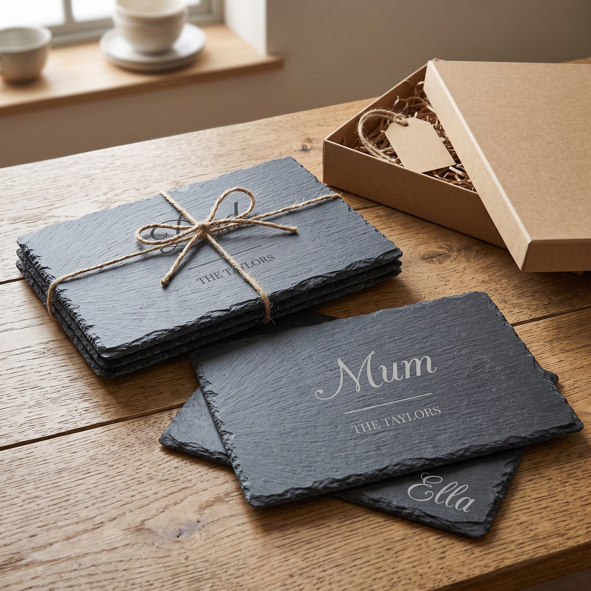 Four engraved slate placemats tied with twine beside a gift box