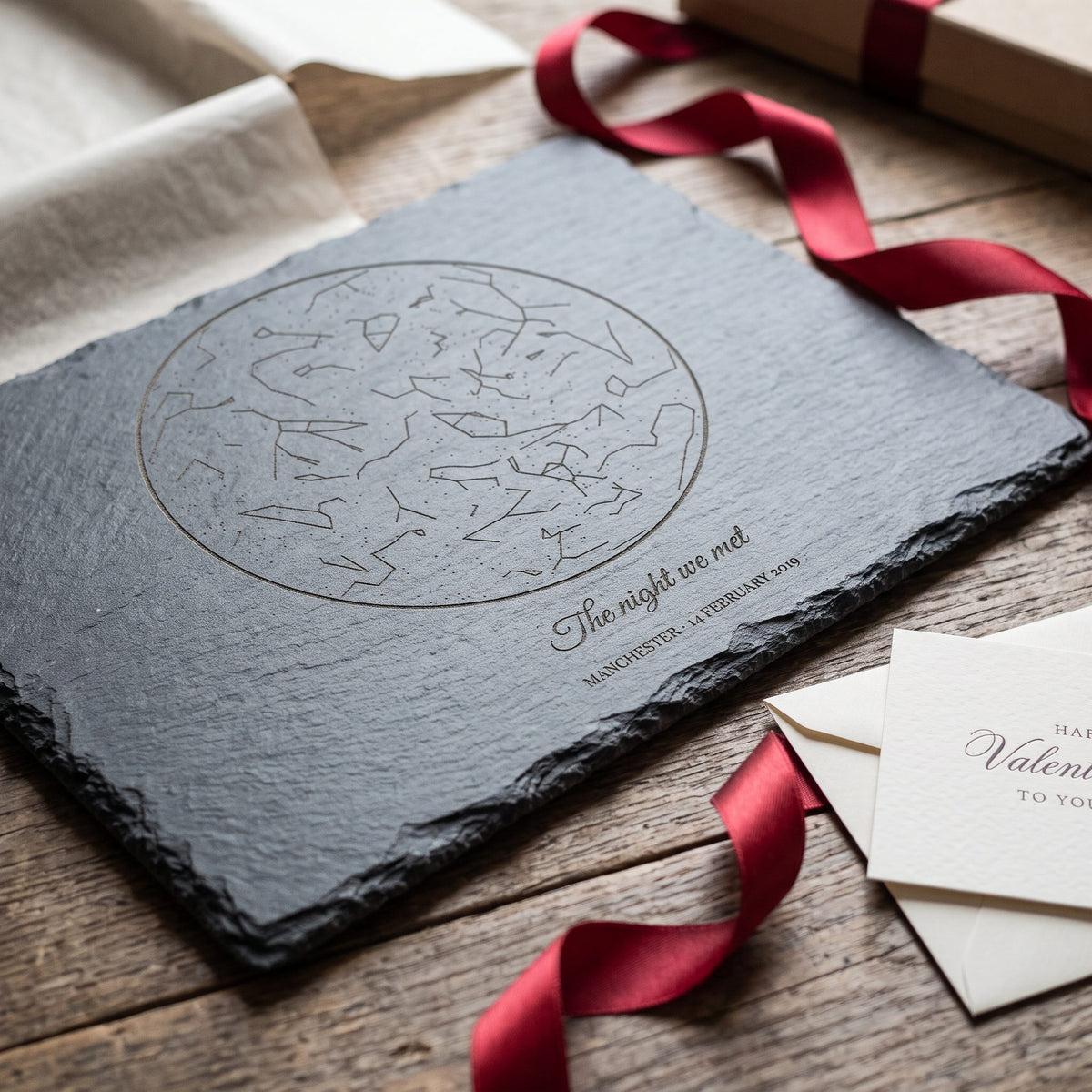 Close-up of an engraved star chart on slate with a red ribbon and Valentine card