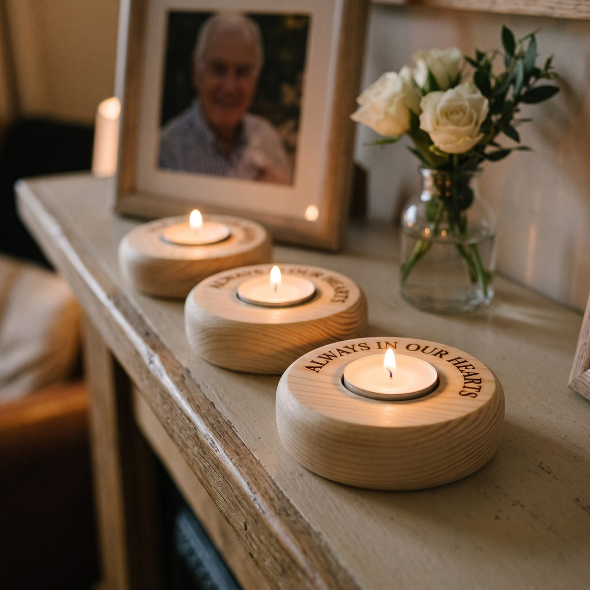 Engraved tea-light holders on a mantelpiece beside a memorial photo