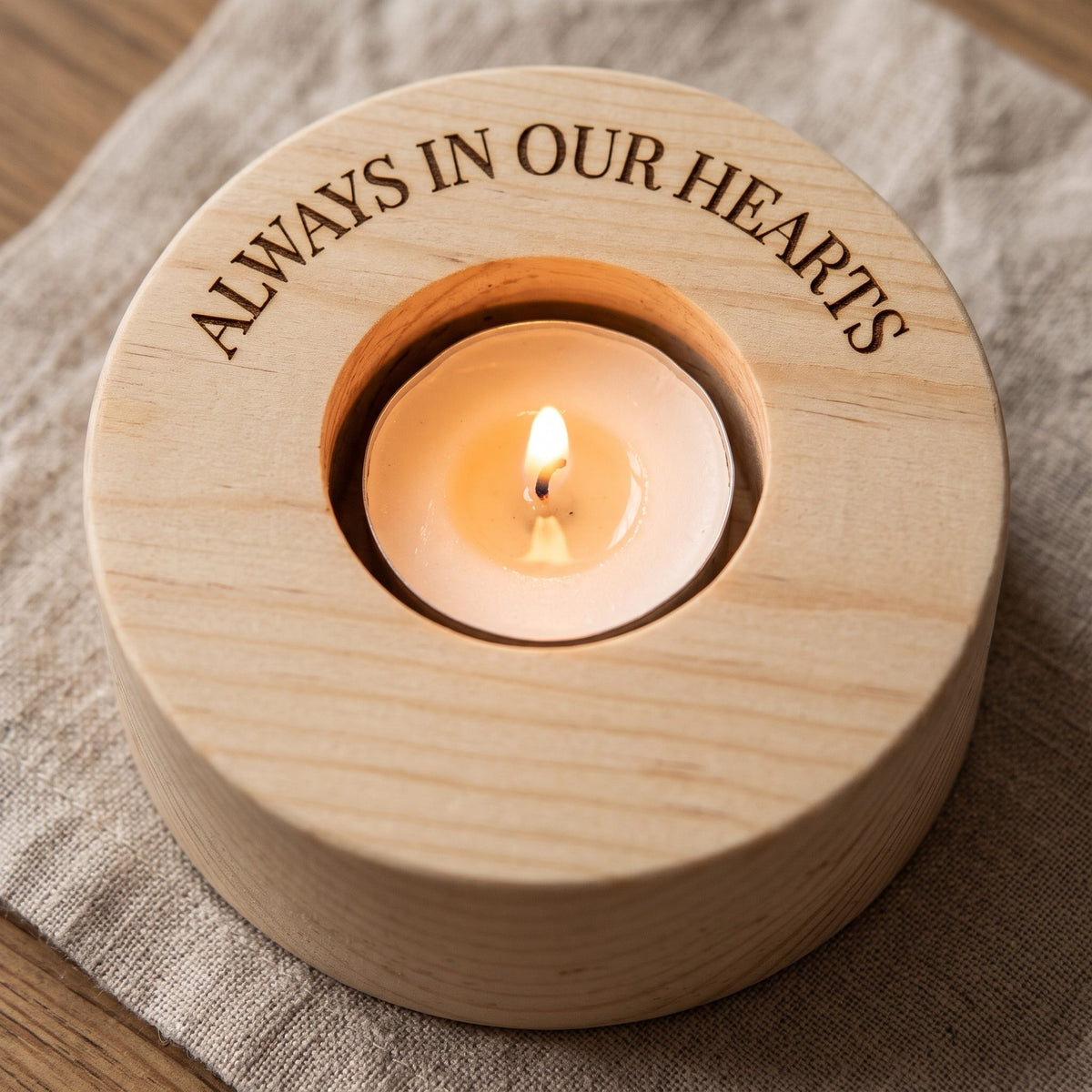 Close-up of a tea-light holder engraved Always in our hearts around the rim