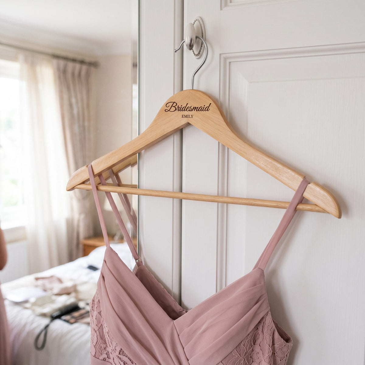 Bridesmaid dress on an engraved wooden hanger on a wardrobe door