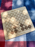 Personalised four in a row game engraved Ali vs Sara, mid-game on a picnic blanket