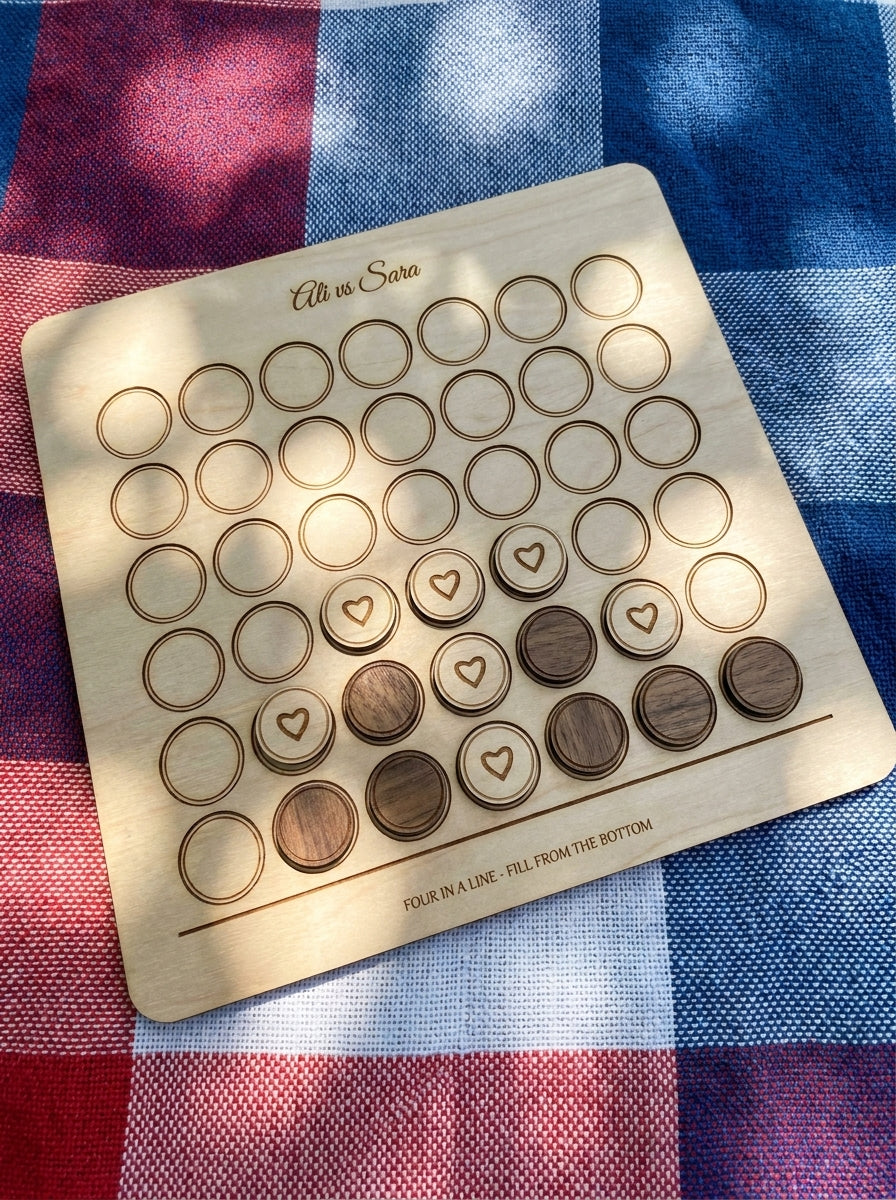 Personalised four in a row game engraved Ali vs Sara, mid-game on a picnic blanket