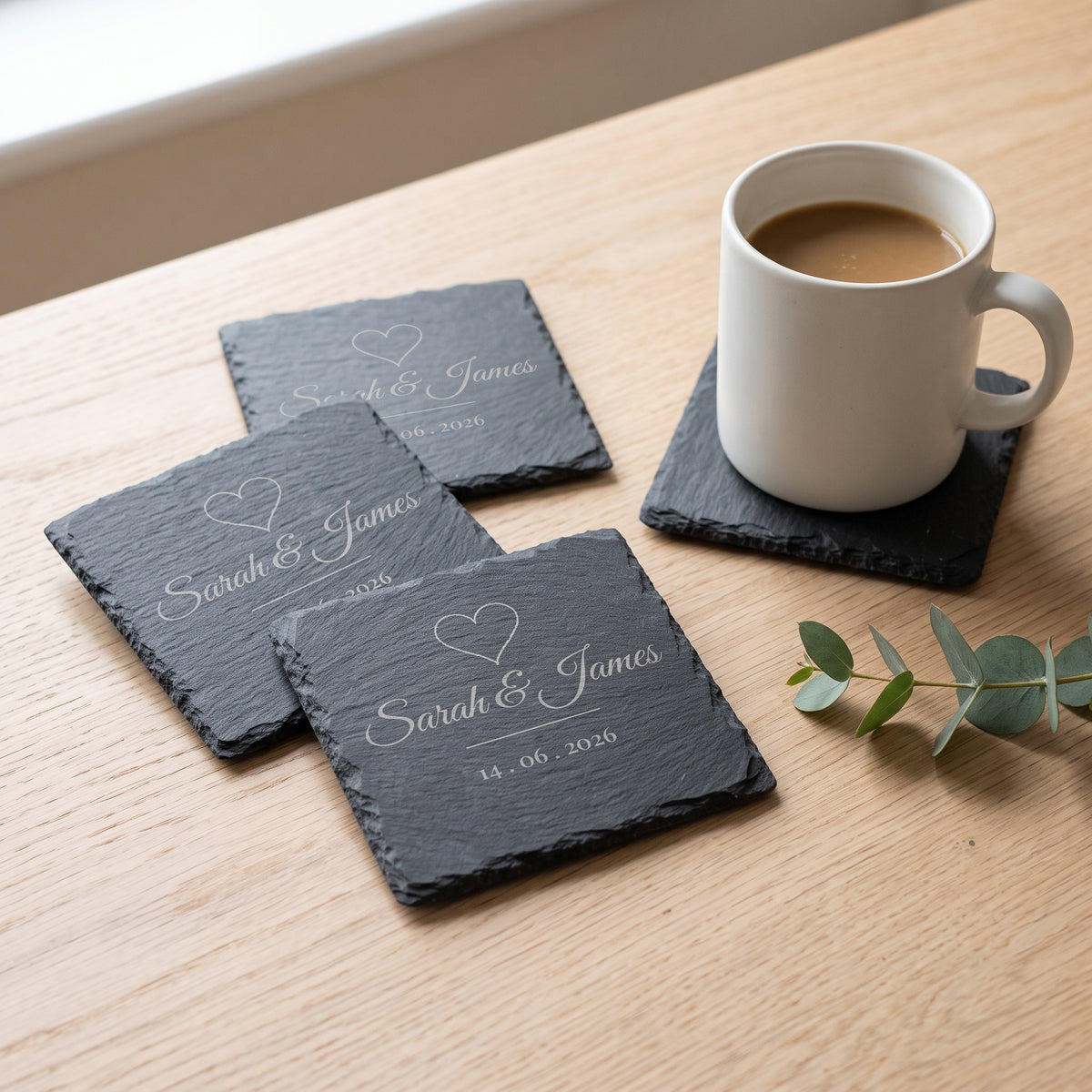 Set of four personalised slate coasters engraved Sarah & James with a heart and wedding date, with a coffee mug