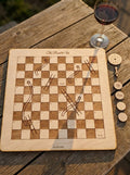 Personalised snakes & ladders board titled The Road to Us, with spinner and named counters on a garden table